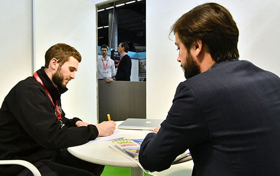 Two people discussing and signing papers around a table